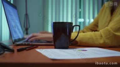 年轻美丽的西班牙妇女洒咖啡在纸上，而工作与笔记本电脑在家里的女孩学习到<strong>深夜</strong>